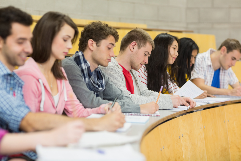 Side view of students writing notes in a row at the college lecture hall-1