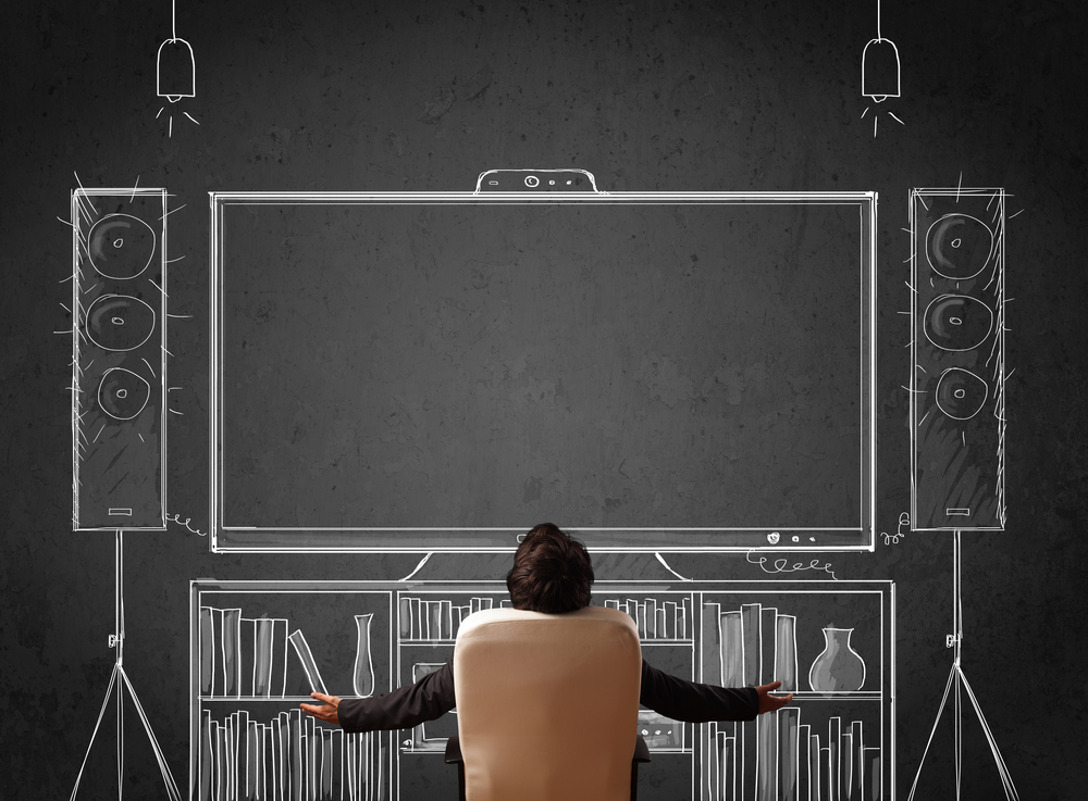 Young businessman sitting and enjoying home cinema system sketched on a chalkboard